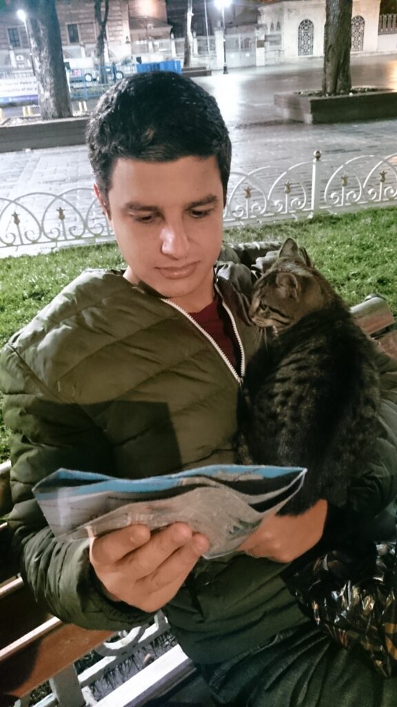 Tiago consultando um mapa em Istambul enquanto um gato decide que queria seu colo